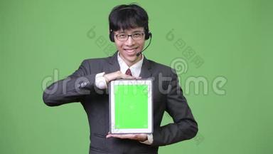 年轻的亚洲商人，在呼叫中心的代表工作时，展示<strong>数码</strong>平板电脑的<strong>摄像头</strong>
